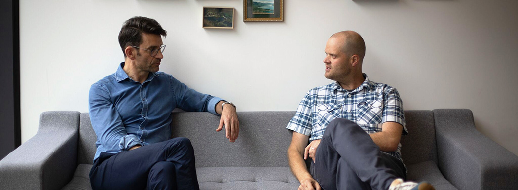 Richard and Giles sitting on a sofa in the cxpartners office, in discussion